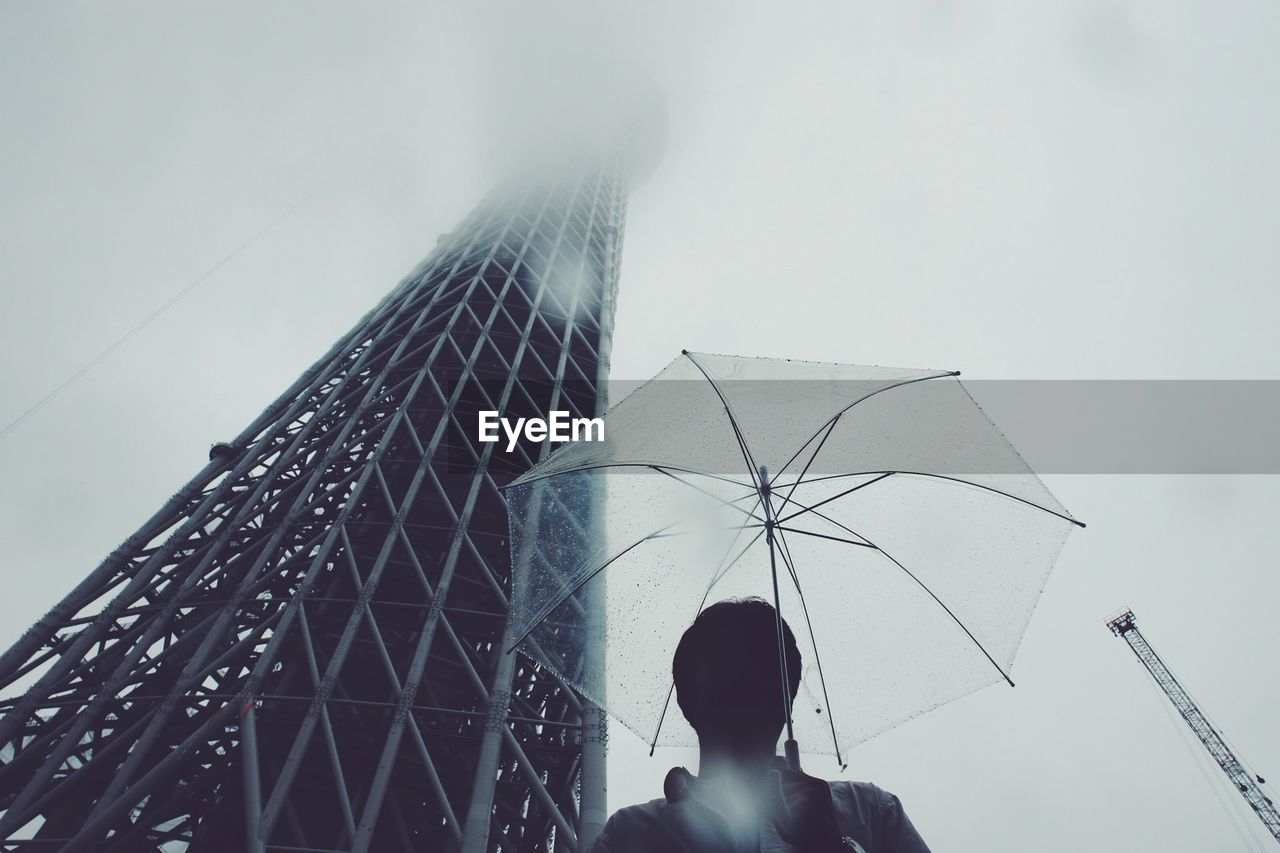 Person holding umbrella under clear sky