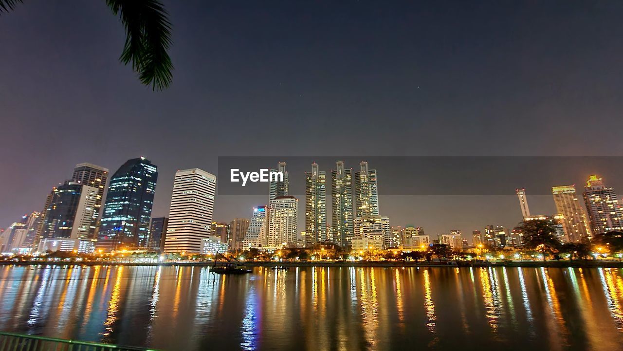 ILLUMINATED MODERN BUILDINGS AGAINST SKY AT NIGHT