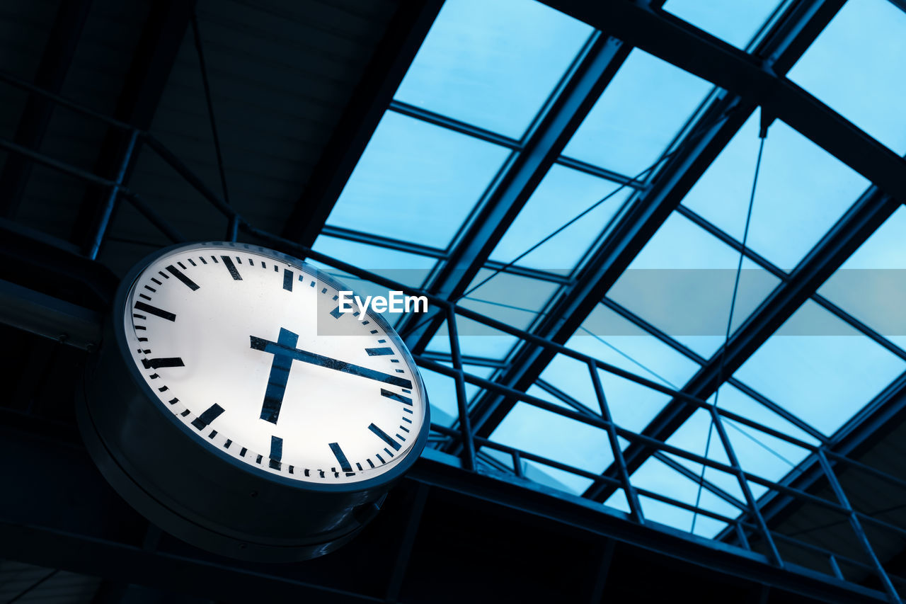 Public indoor clock and skyroof in train station at twilight, clock show time at rush hour