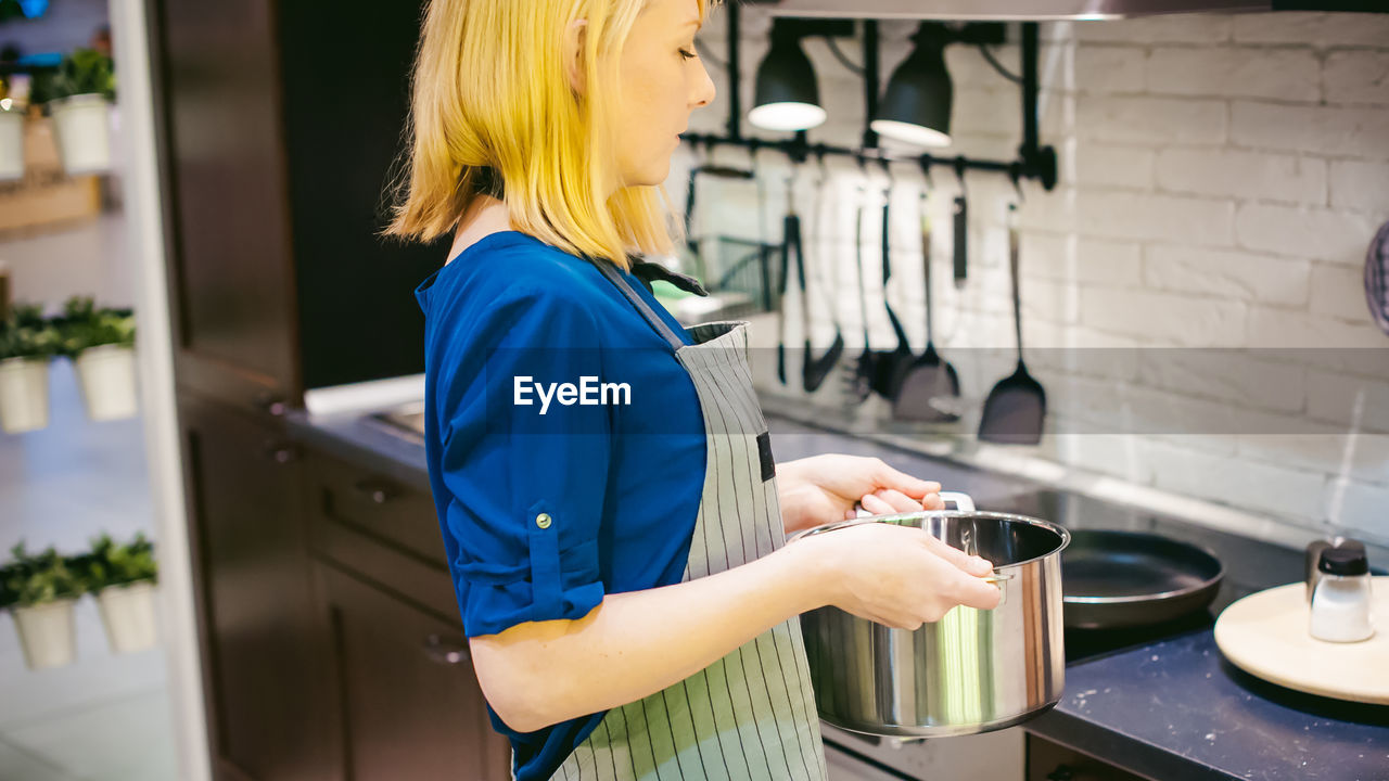 Side view of young woman working in kitchen