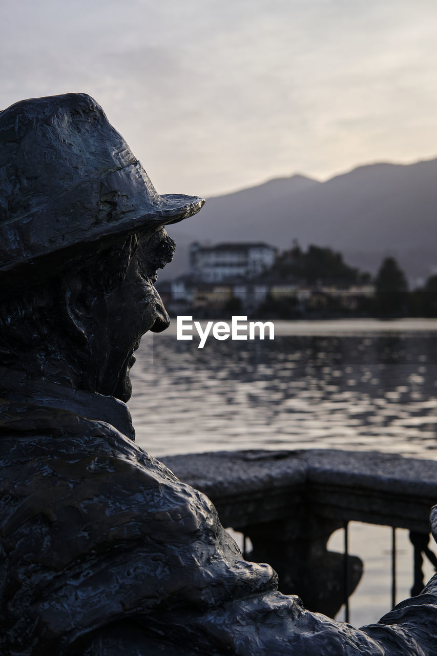 CLOSE-UP OF STATUE AGAINST SEA AND MOUNTAIN