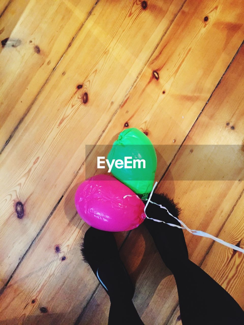 Low section of woman by balloons on wooden plank