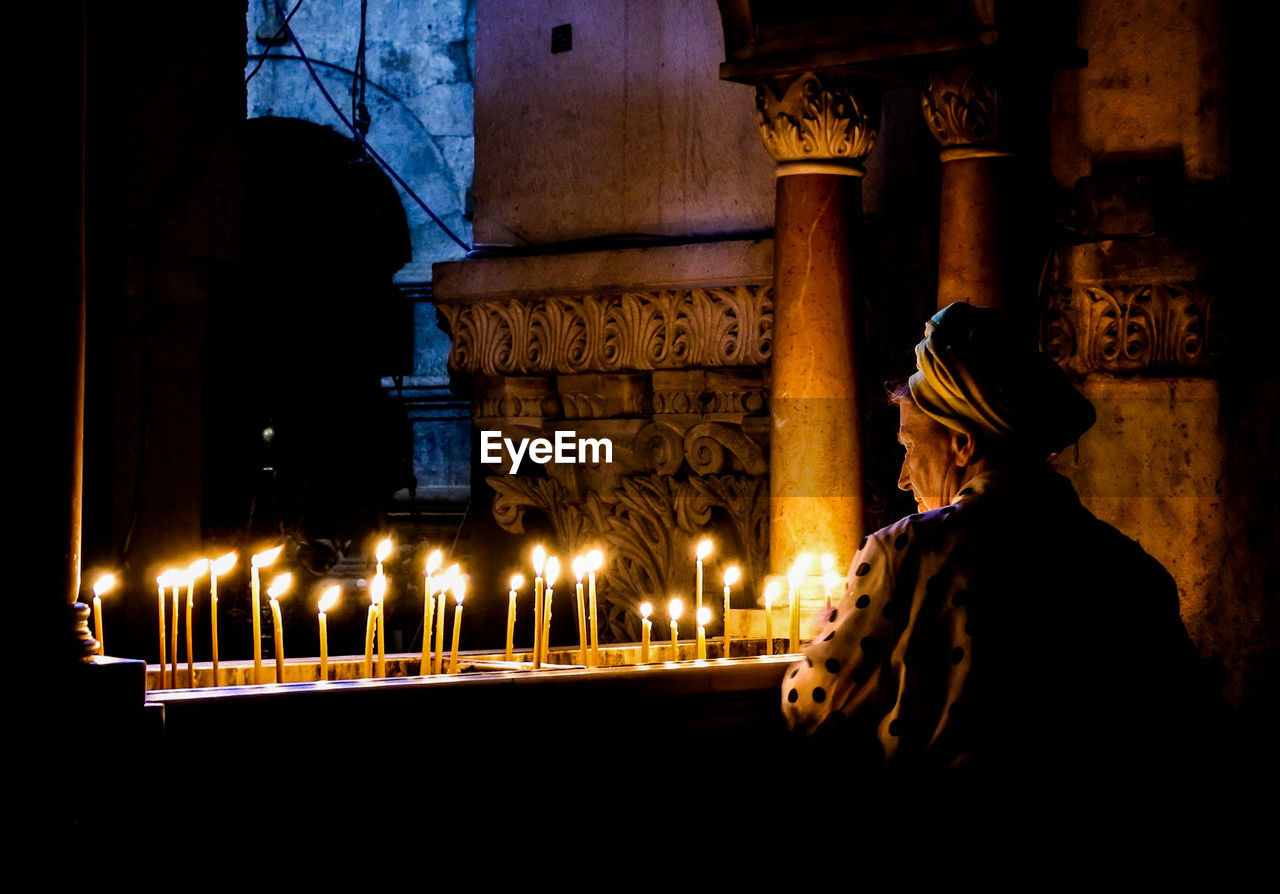 Old lady lights the. candles at the holy sepulcher of jerusalem