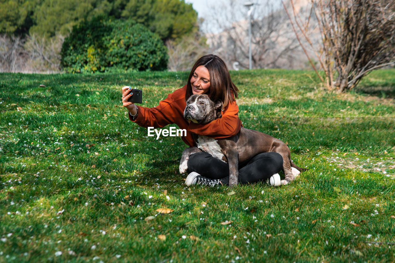 Portrait of young woman with dog on field