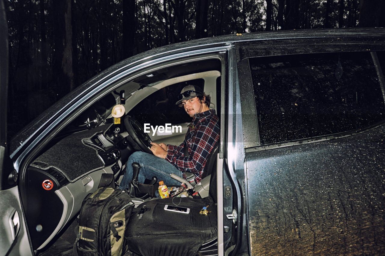 PORTRAIT OF MAN SITTING IN CAR