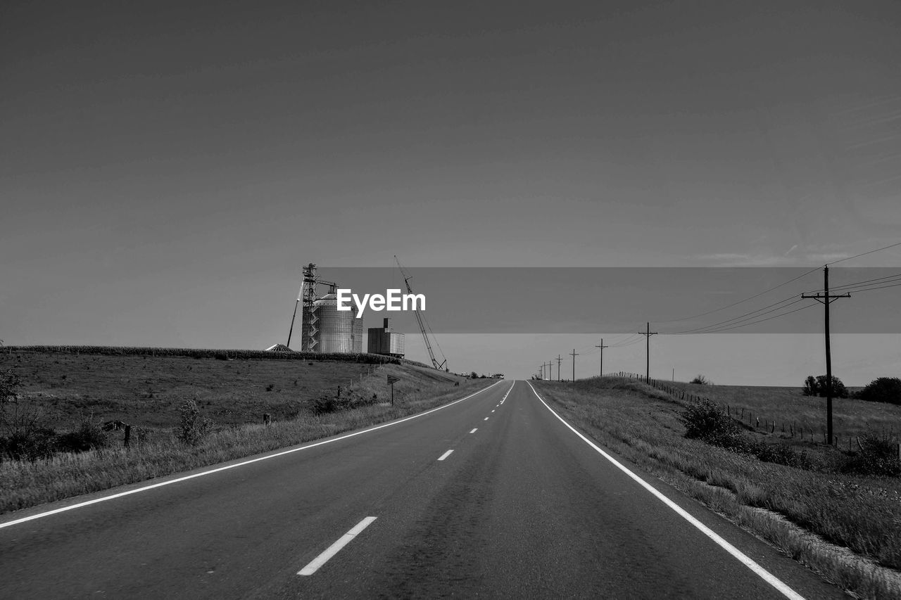 ROAD BY ELECTRICITY PYLONS AGAINST SKY