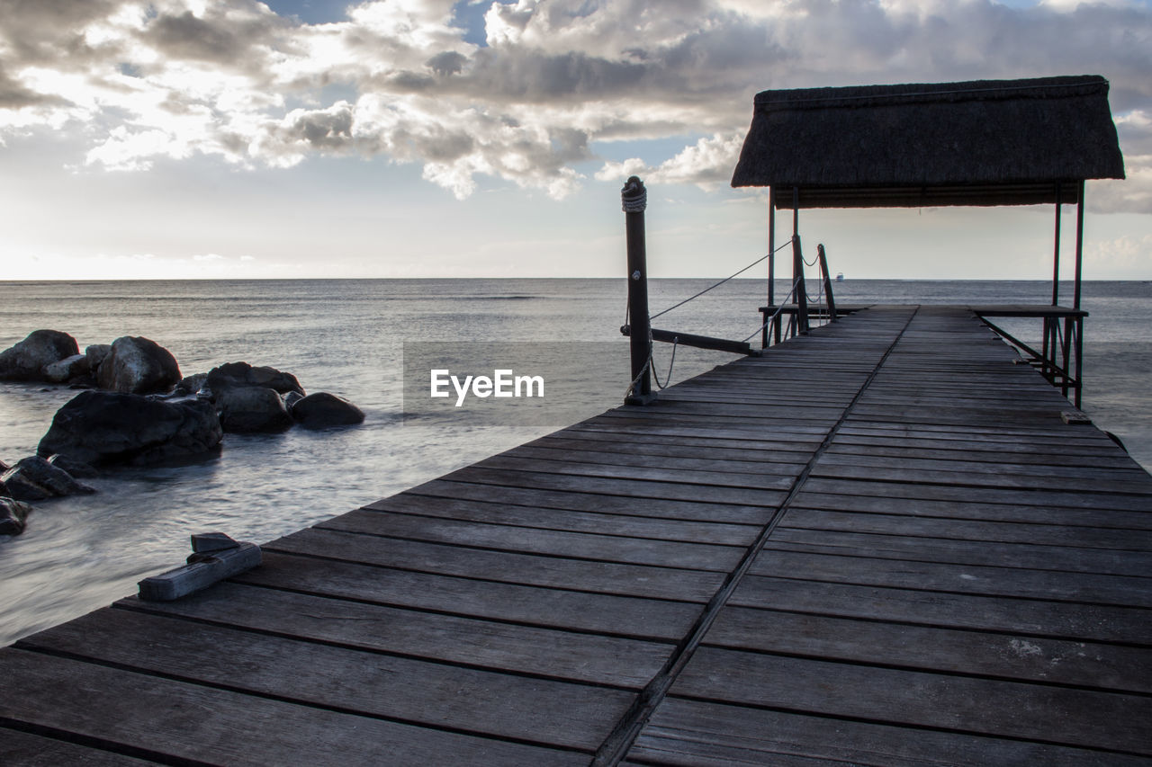 Jetty leading towards sea against sky