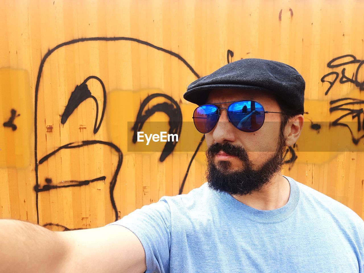 Man wearing sunglasses while standing against graffiti wall