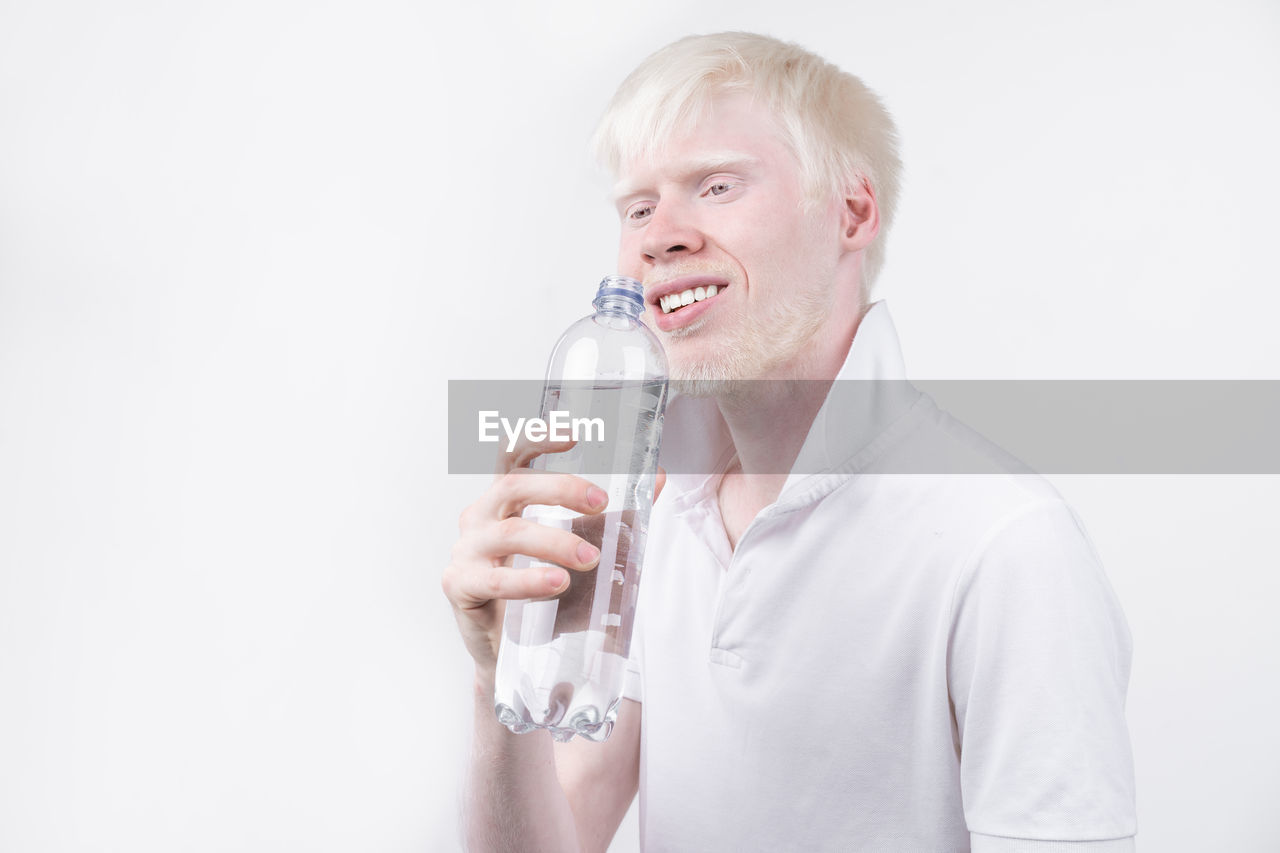 Man with albino holding water bottle against white background