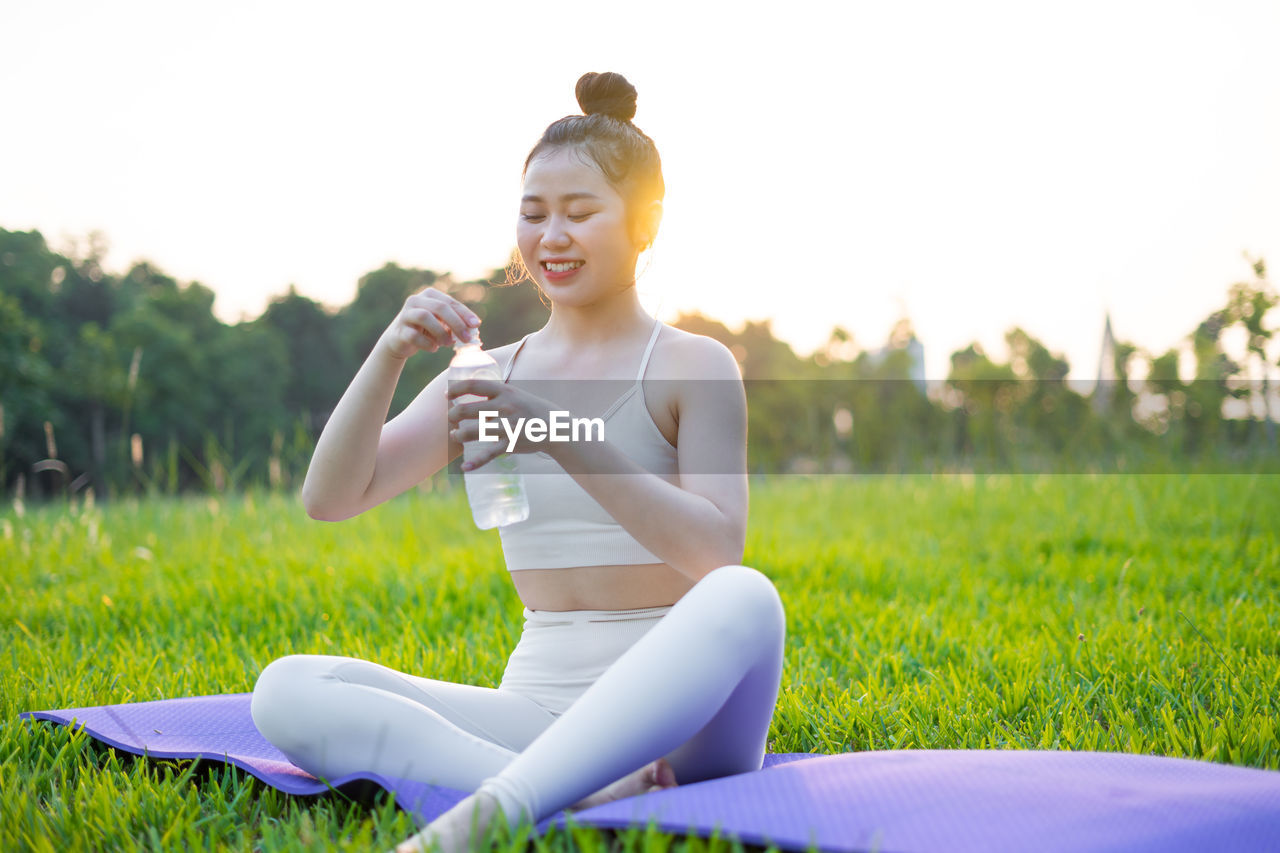 side view of young woman sitting on field