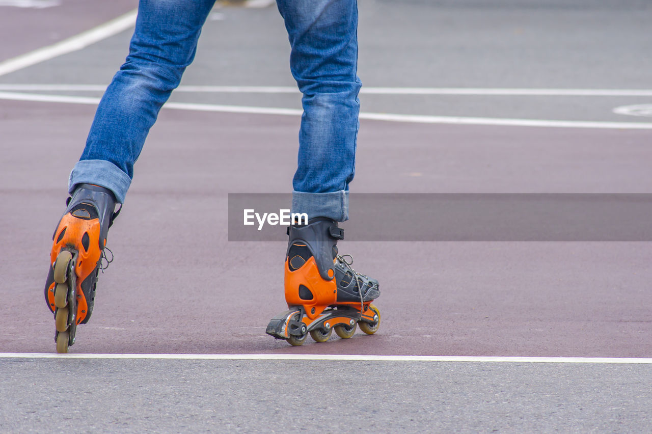 Low section of man inline skating on road