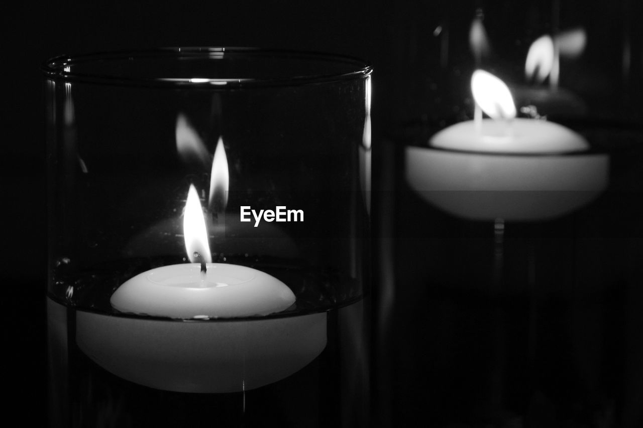 Close-up of lit candles in glasses