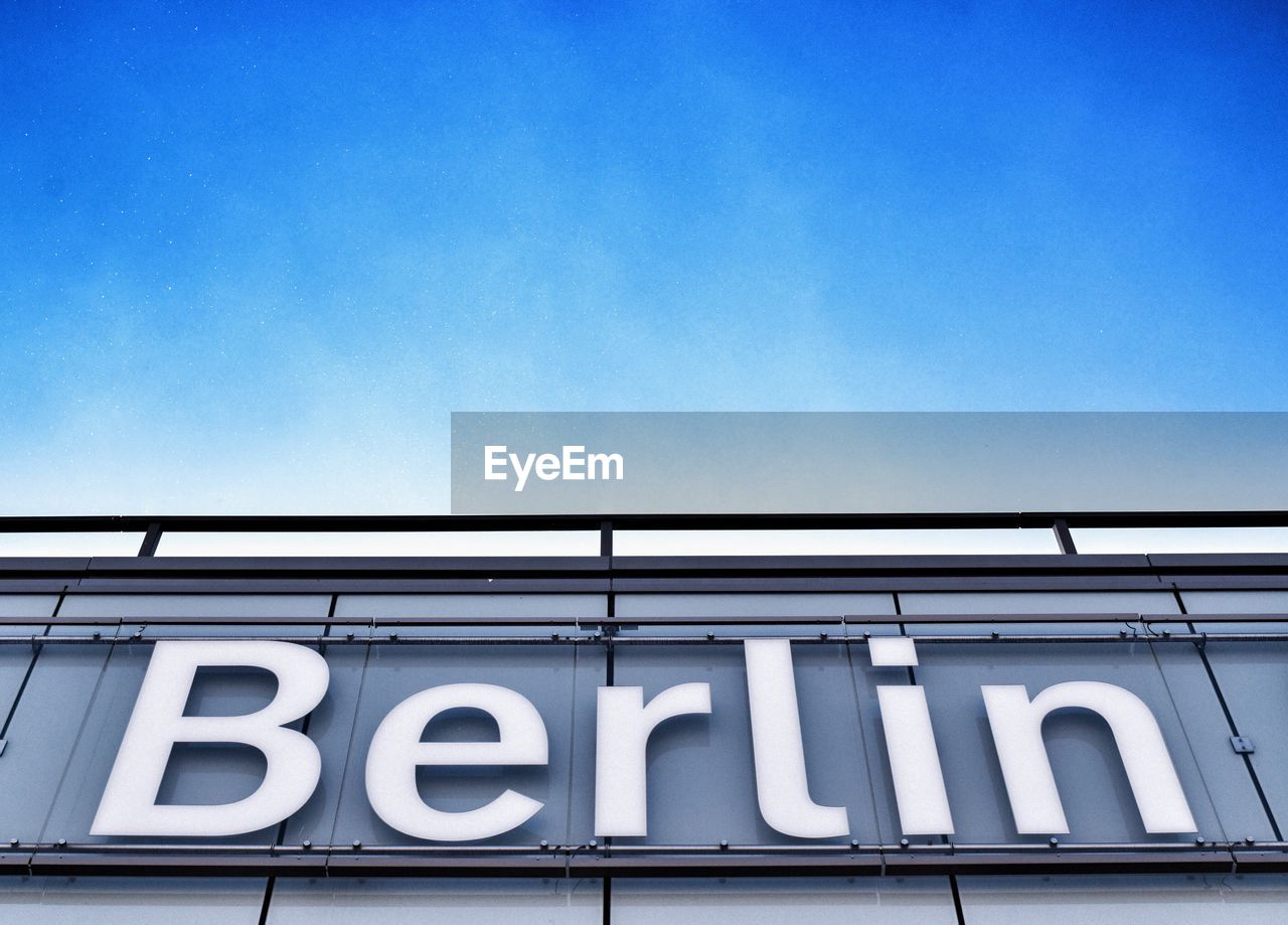 Low angle view of berlin text on wall against sky