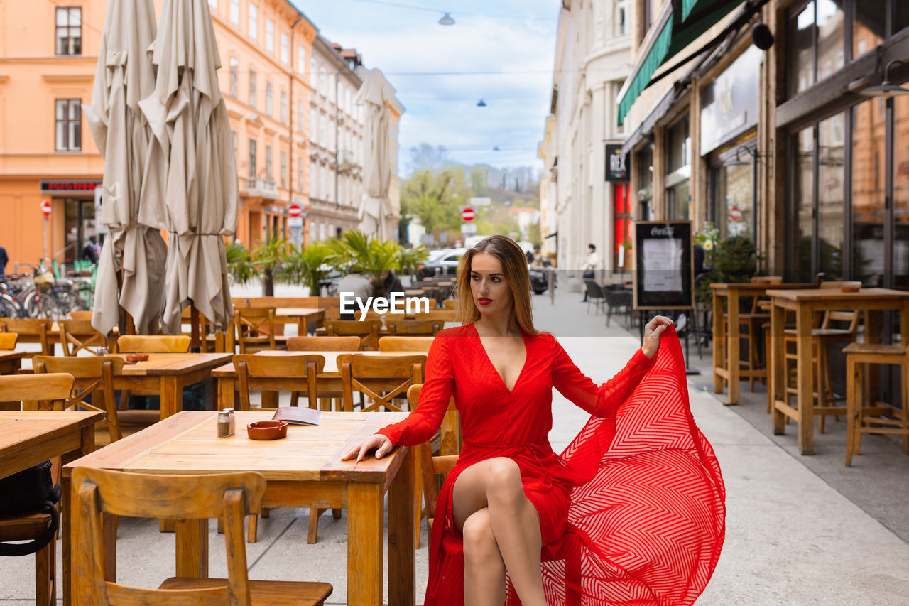 portrait of young woman using mobile phone while sitting on chair