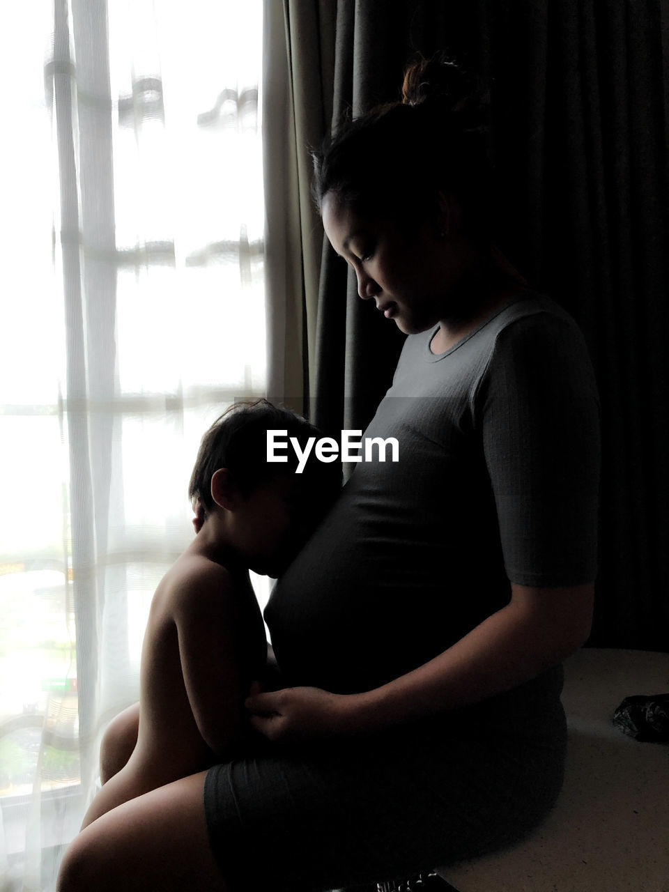 Mother and son while sitting on window