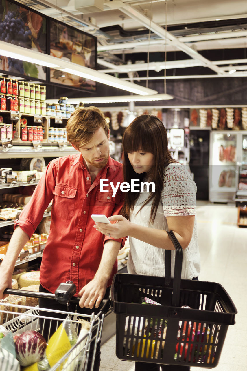 Couple using mobile phone at supermarket