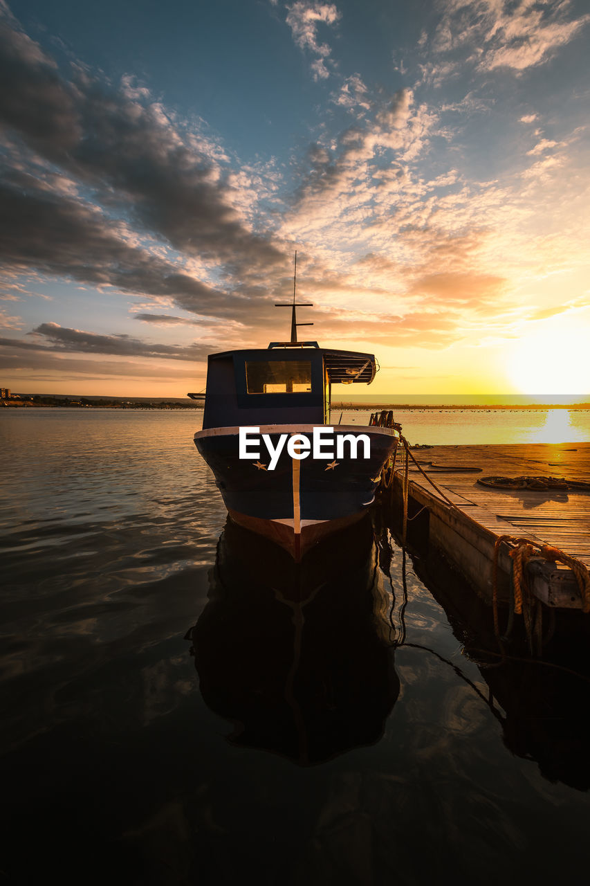 Boat moored in the port of taranto vecchia with the rising sun behind it