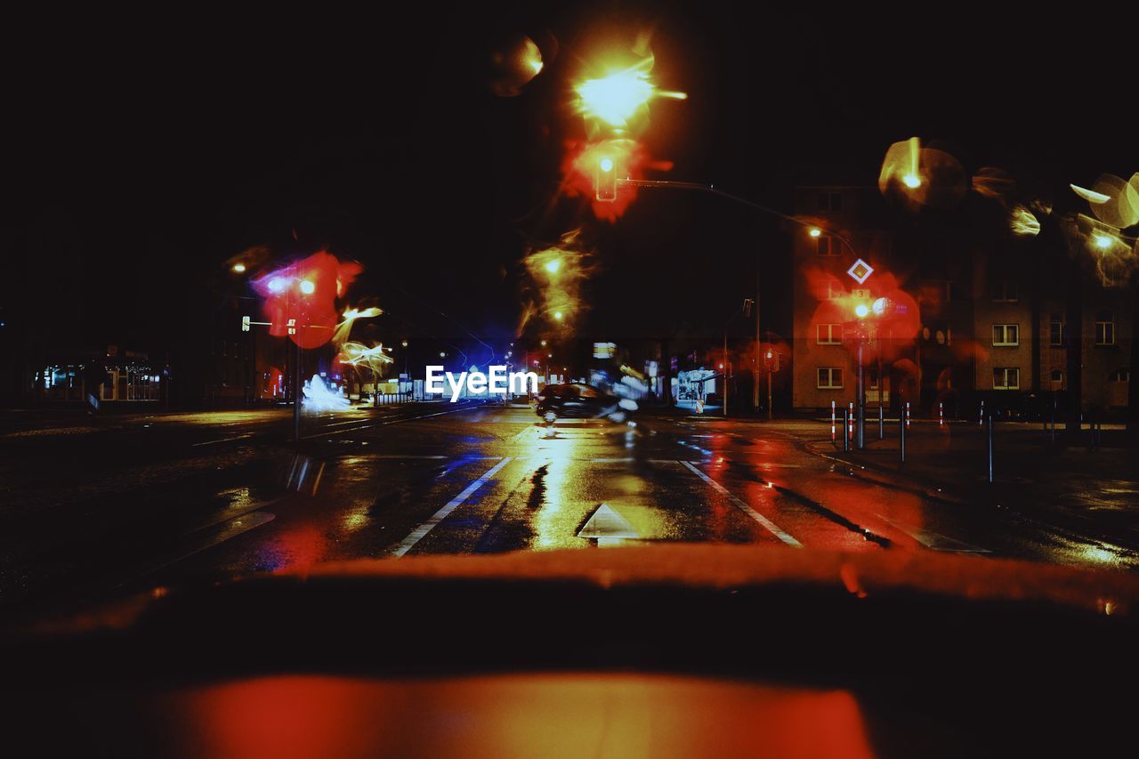 CARS ON ILLUMINATED ROAD IN CITY AT NIGHT