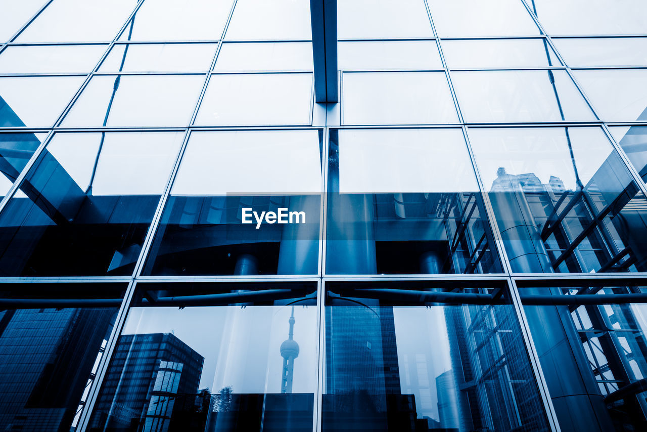 LOW ANGLE VIEW OF MODERN GLASS BUILDINGS AGAINST SKY