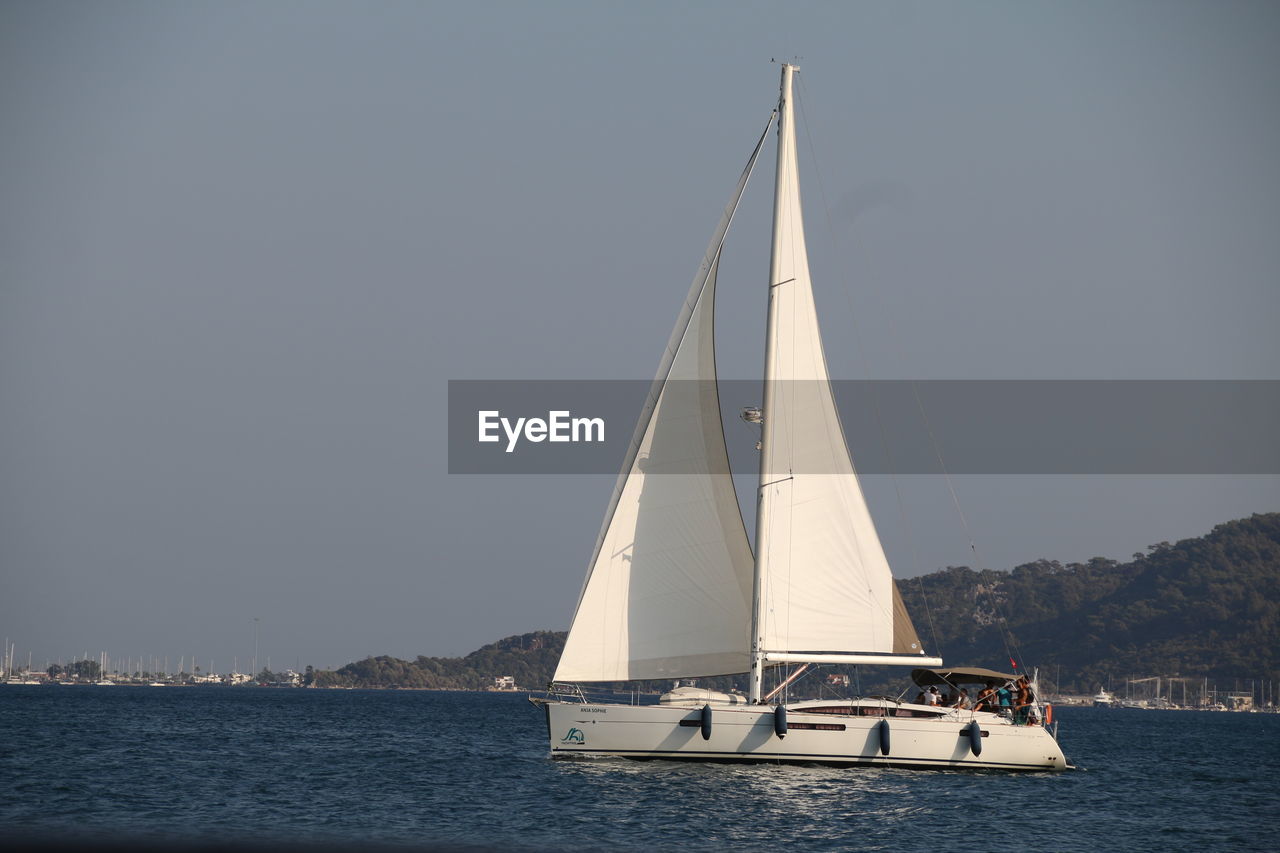 SAILBOATS SAILING IN SEA AGAINST CLEAR SKY