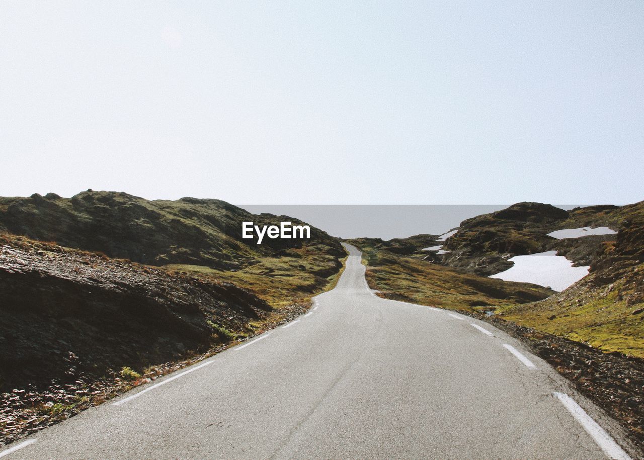 Road amidst mountains against clear sky