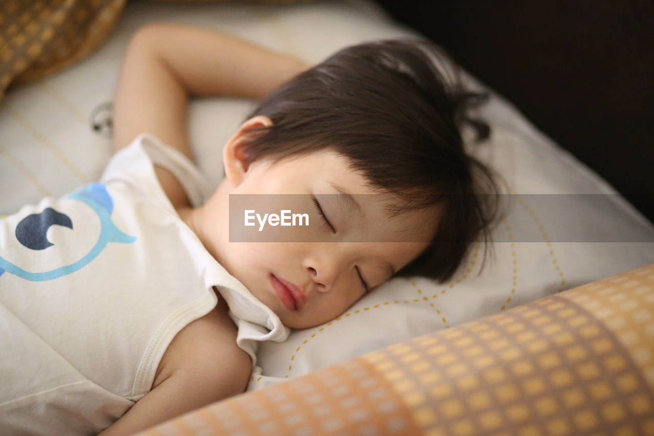 High angle view of boy sleeping on bed