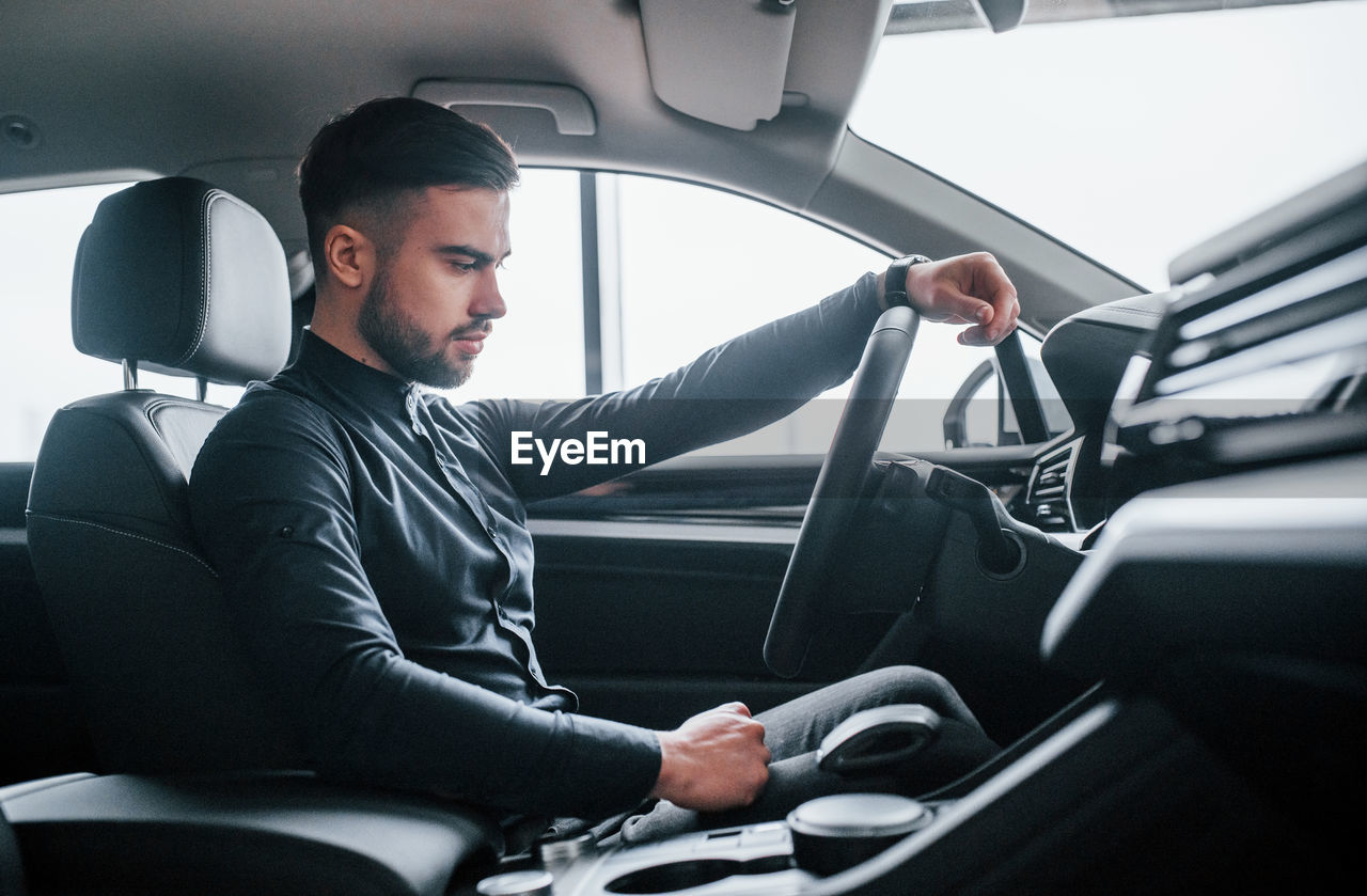 rear view of man using mobile phone while sitting in car