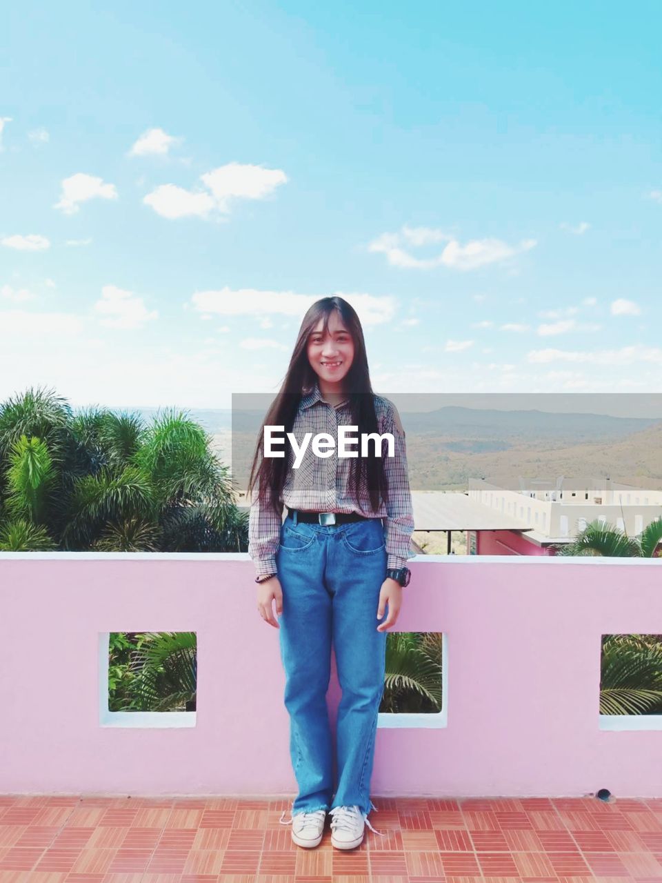 Portrait of smiling young woman standing against sky