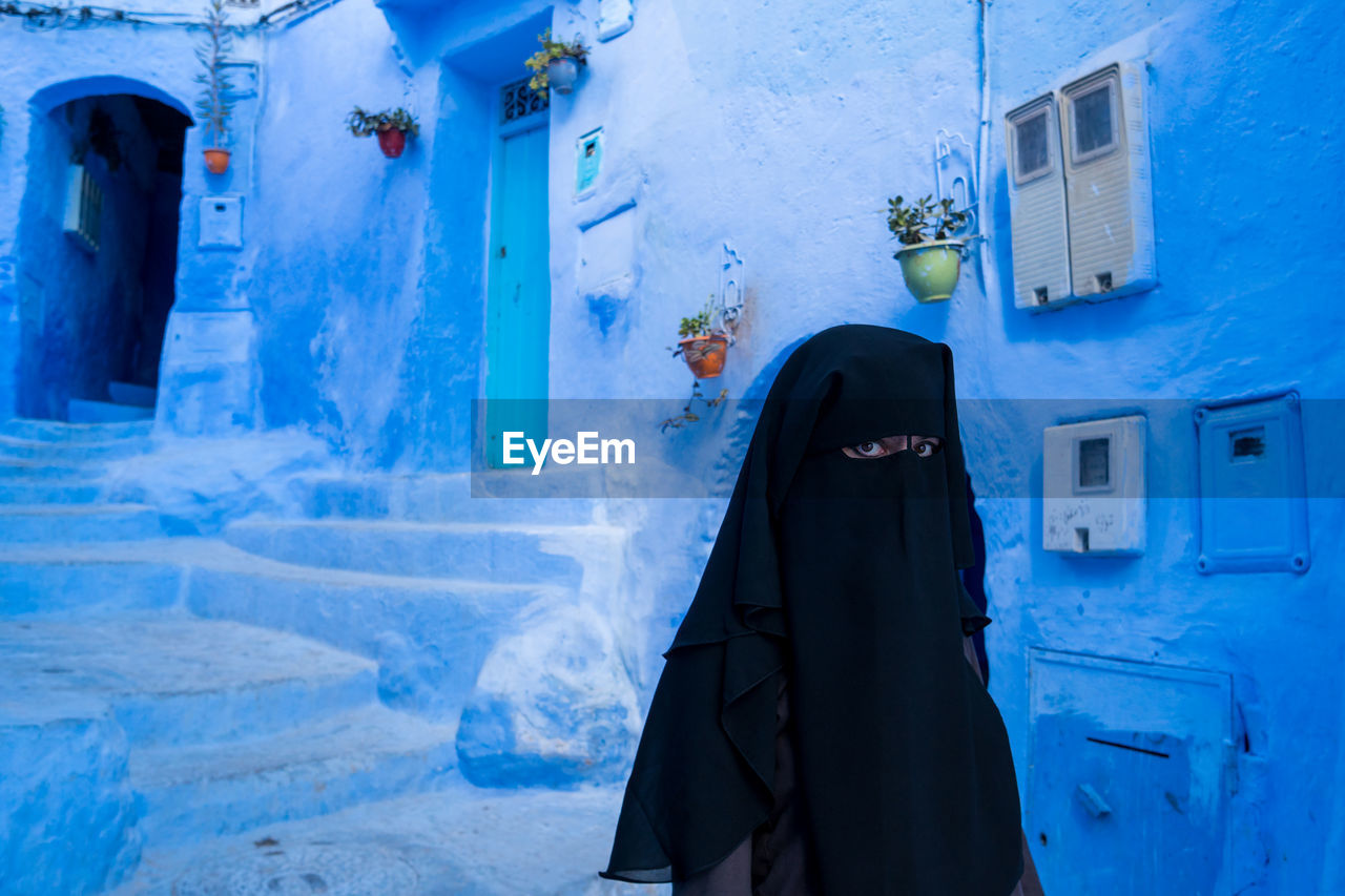 Portrait of woman wearing burka standing against building 