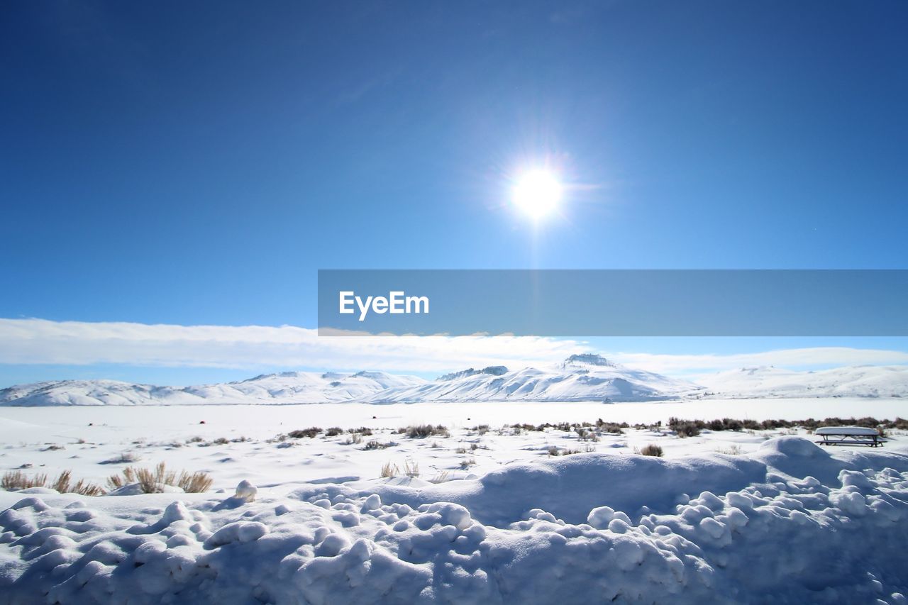 Scenic view of snow covered mountains against blue sky