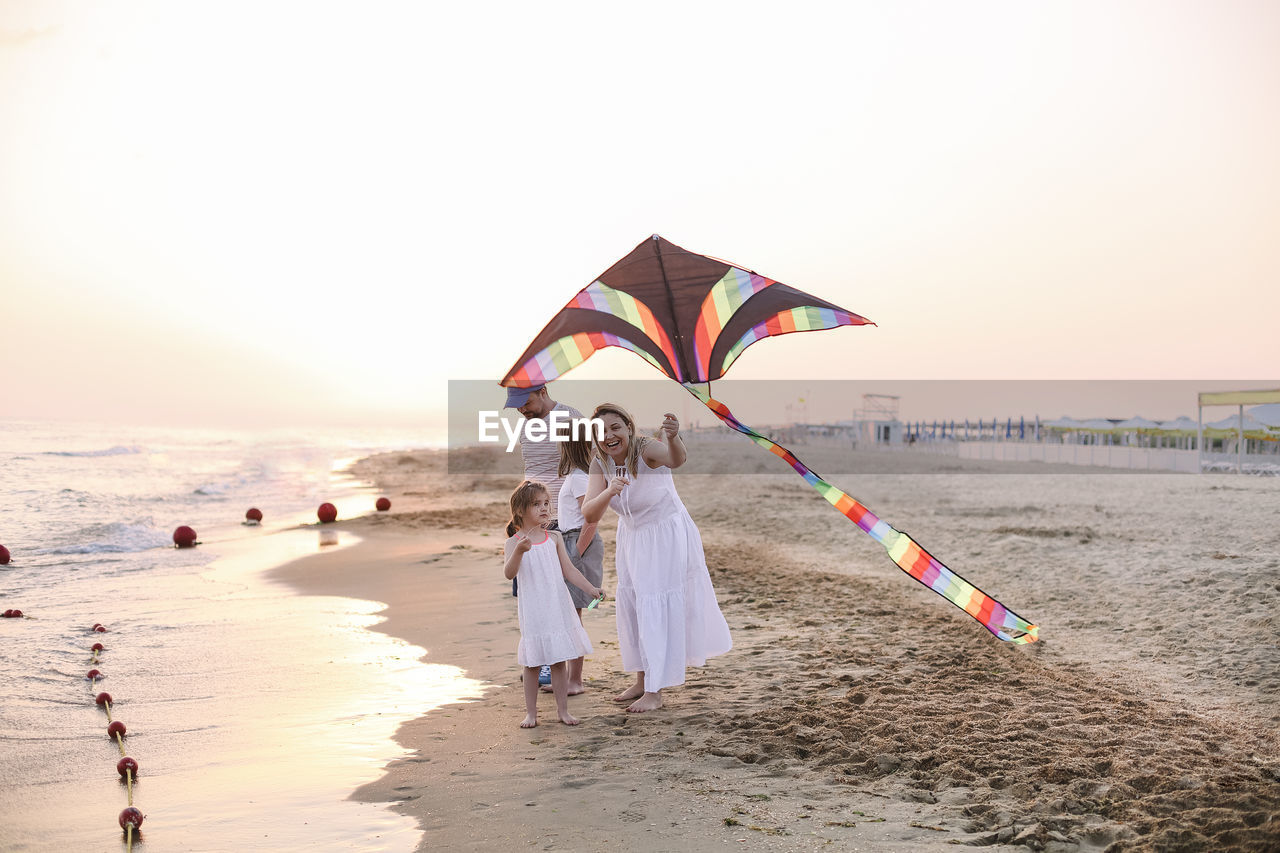 Mother and daughter flying kites on beach