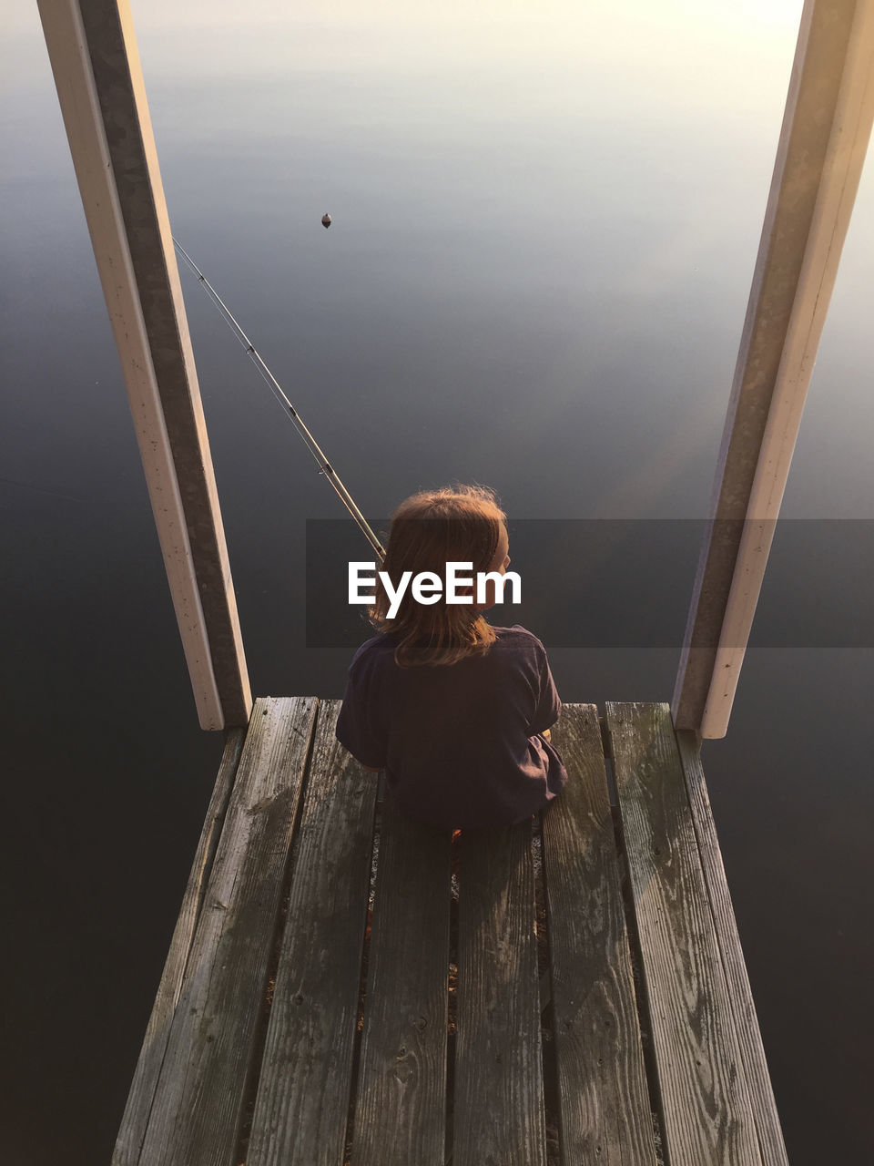 High angle view of girl fishing while sitting on pier over kentucky lake