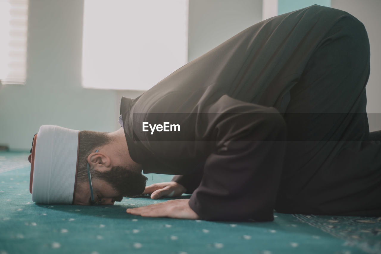 YOUNG MAN SLEEPING ON FLOOR IN BEDROOM