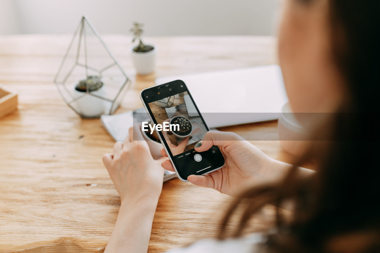 A young woman takes photos of objects goods things using a mobile phone creates content for a blog