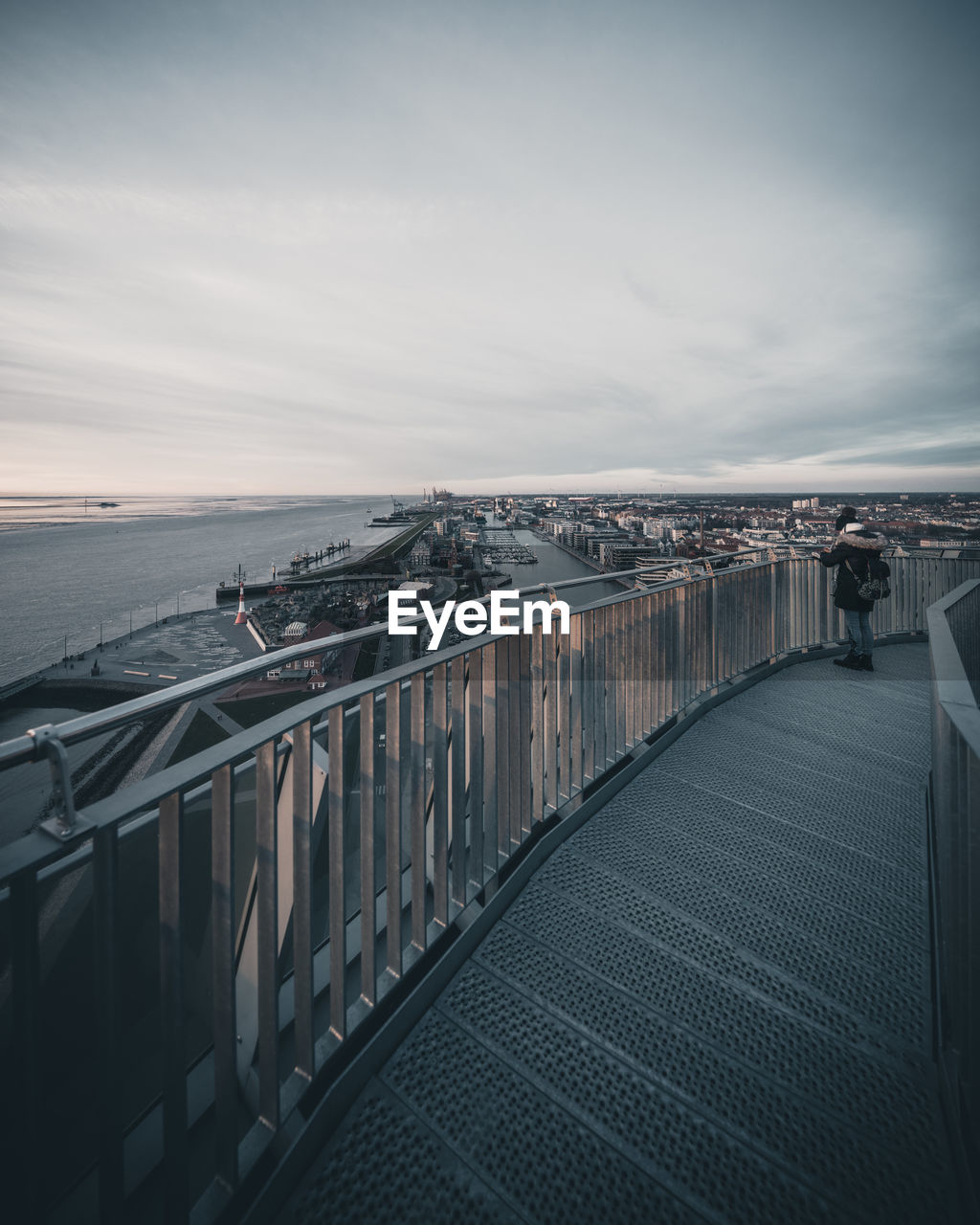 MAN WALKING ON BRIDGE AGAINST SKY