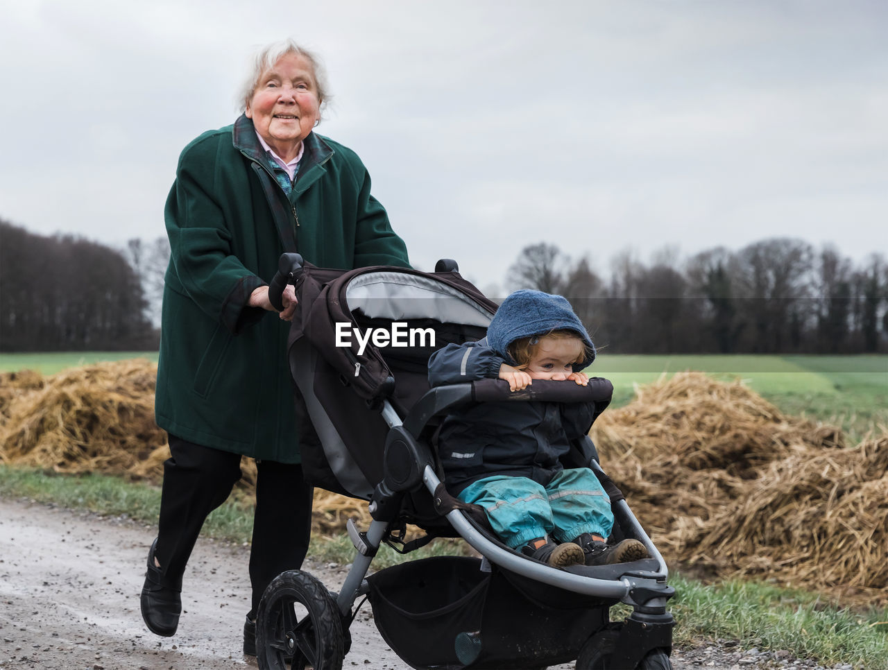 Full length of grandmother pushing baby stroller with granddaughter