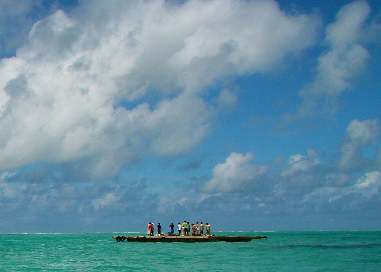 TOURISTS ON BOAT IN SEA AGAINST CLOUDY SKY