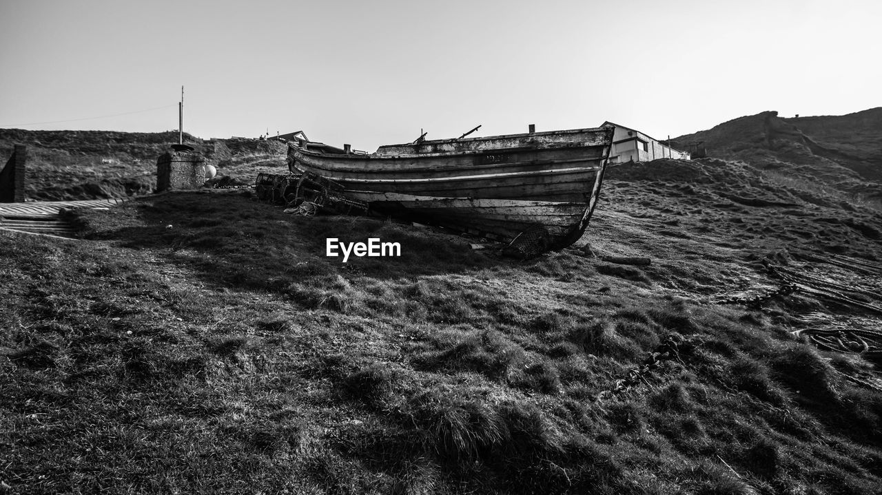 ABANDONED BOAT ON SHORE AGAINST SKY