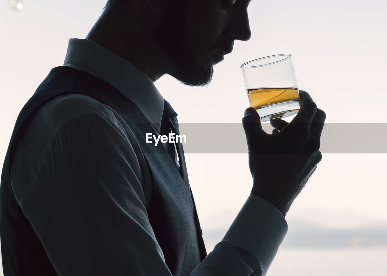 Man holding drink glass against white background