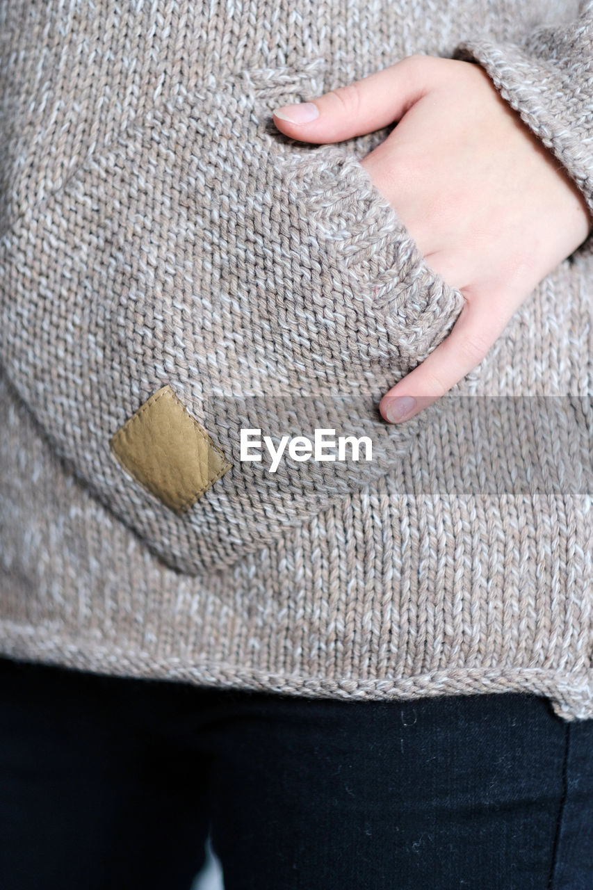 Hand in pocket. close-up fashionable casual gray and beige wool sweater and jeans on a female body.