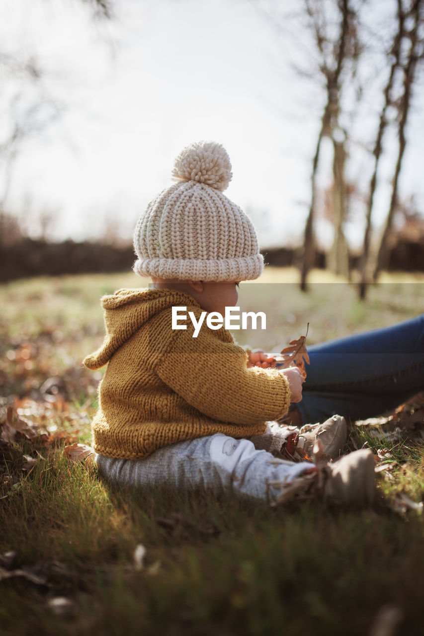 Mother and daughter wearing warm clothing while sitting on land