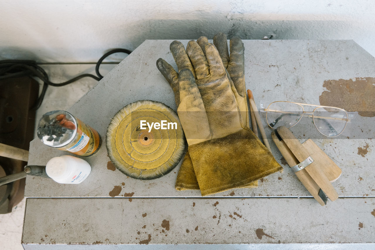 Dirty gloves rest by glasses and assorted crafting tools and resources
