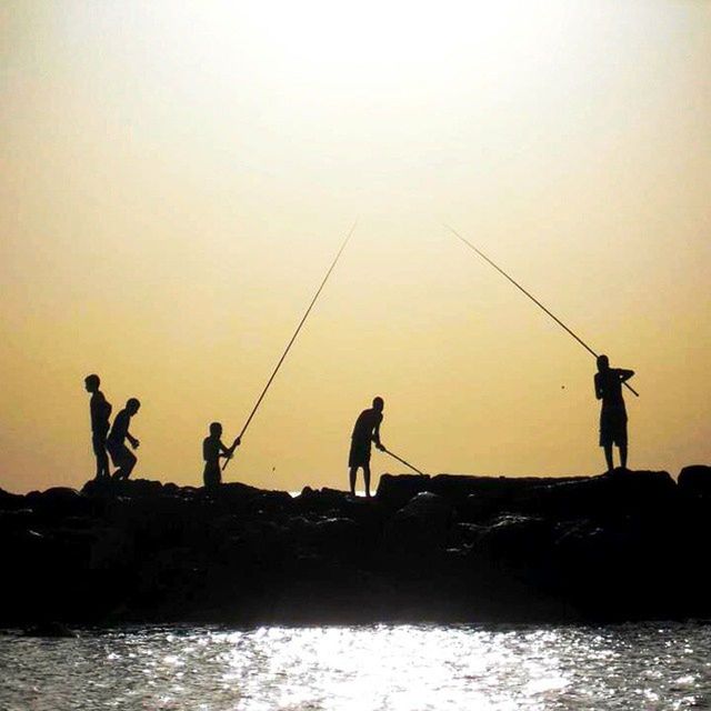 SILHOUETTE OF PEOPLE FISHING IN SEA