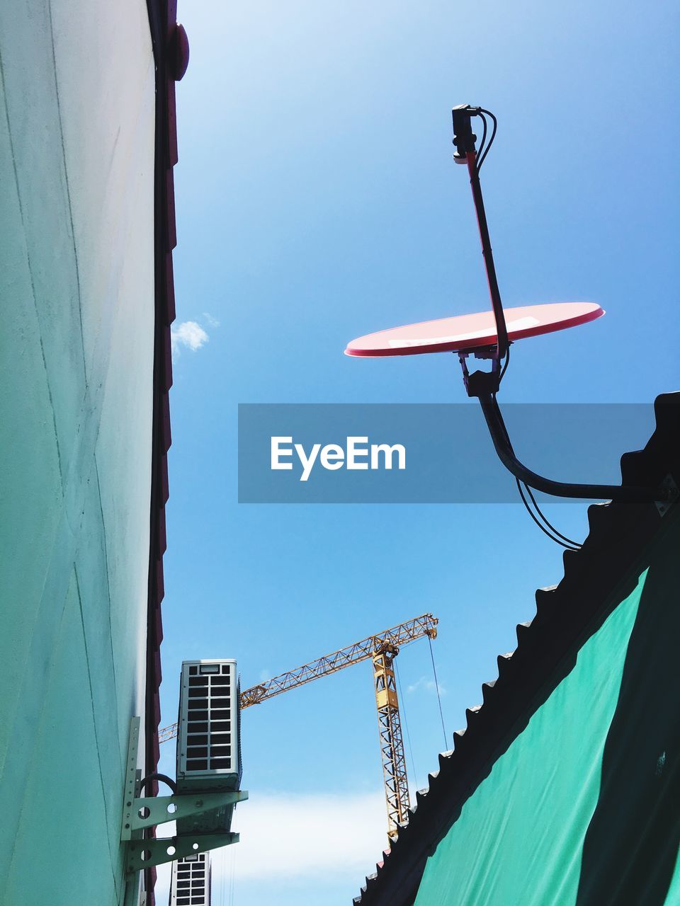 LOW ANGLE VIEW OF CRANE BY BUILDING AGAINST SKY