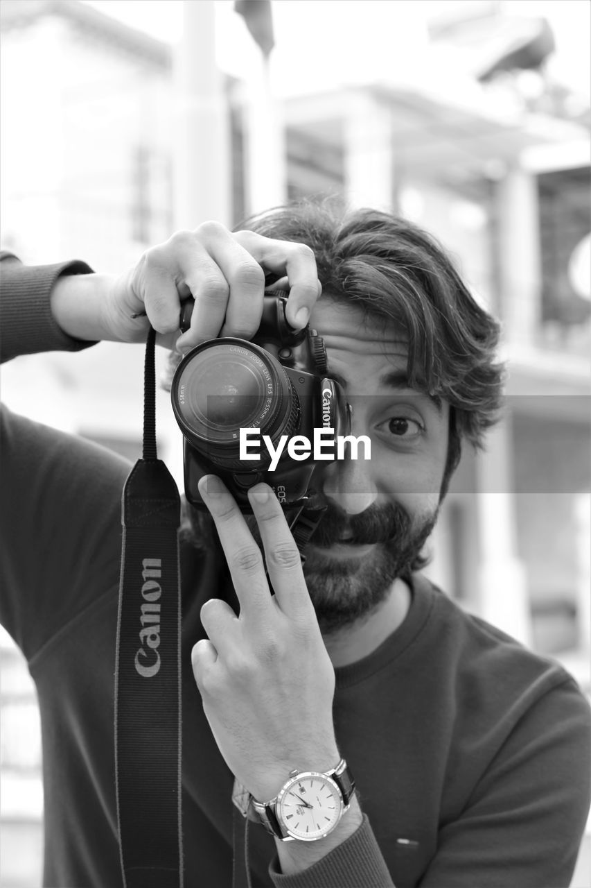 PORTRAIT OF YOUNG MAN PHOTOGRAPHING CAMERA