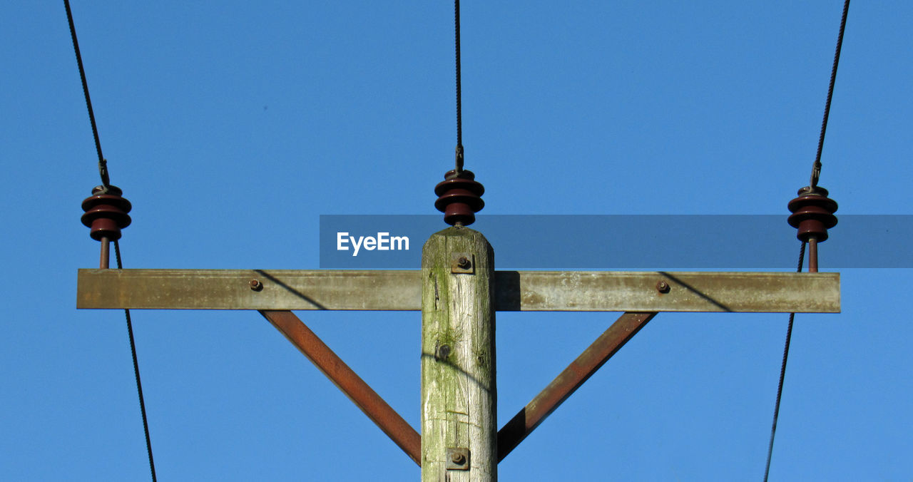 LOW ANGLE VIEW OF TELEPHONE POLE AGAINST CLEAR BLUE SKY