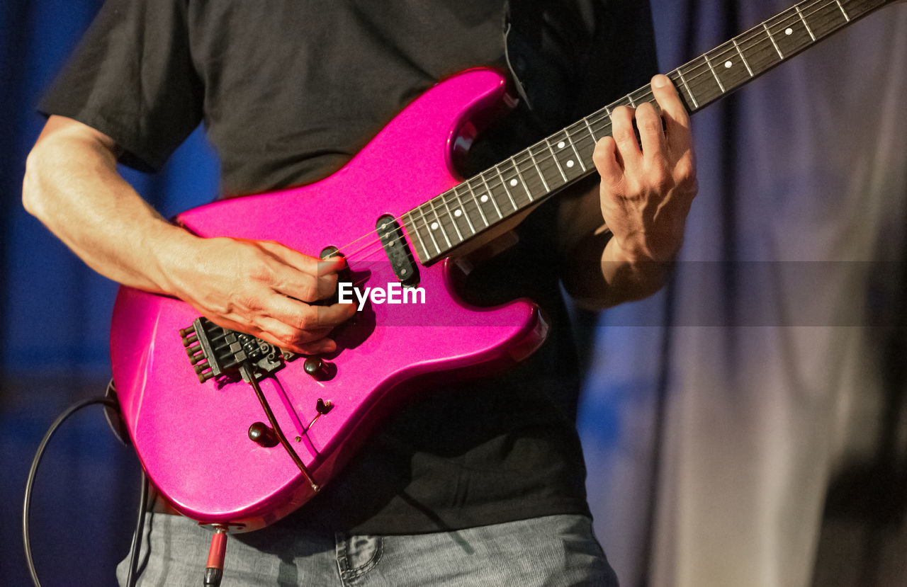 Midsection of man playing guitar