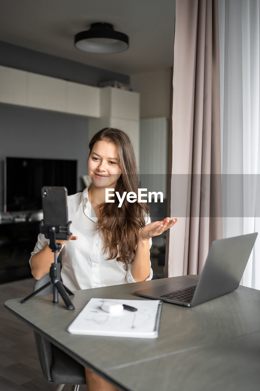 portrait of young woman using mobile phone while sitting in office