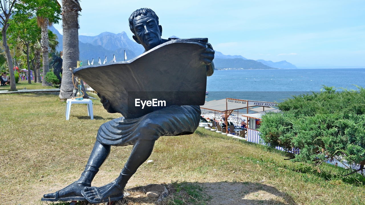 Statue by sea against sky