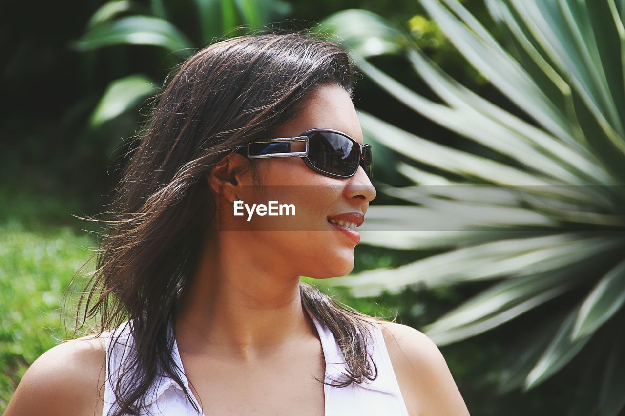 Close-up of young woman wearing sunglasses against plants